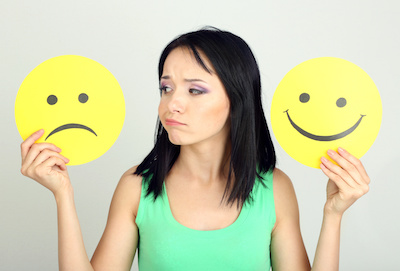 Young woman holding paper with sad and happy smiley Happy Unhappy